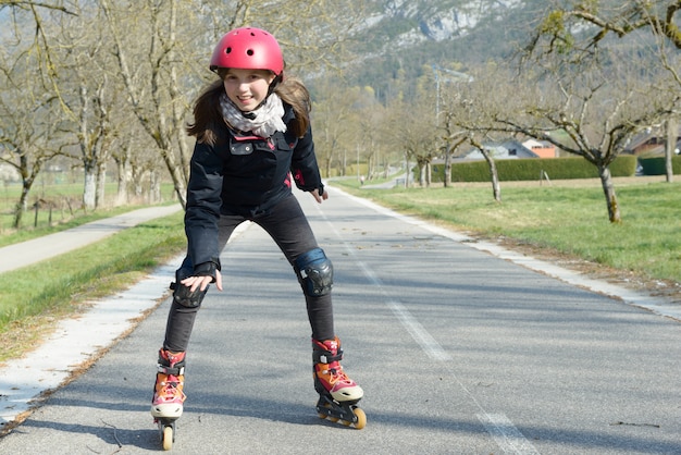 Menina bonita pré-adolescente de patins no capacete em uma pista