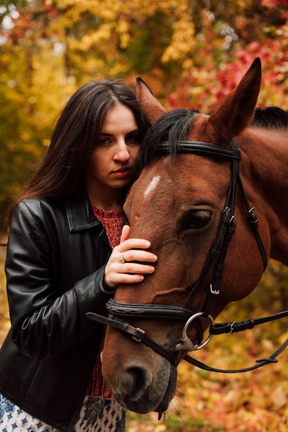 Menina bonita pressionando a cabeça contra um cavalo marrom