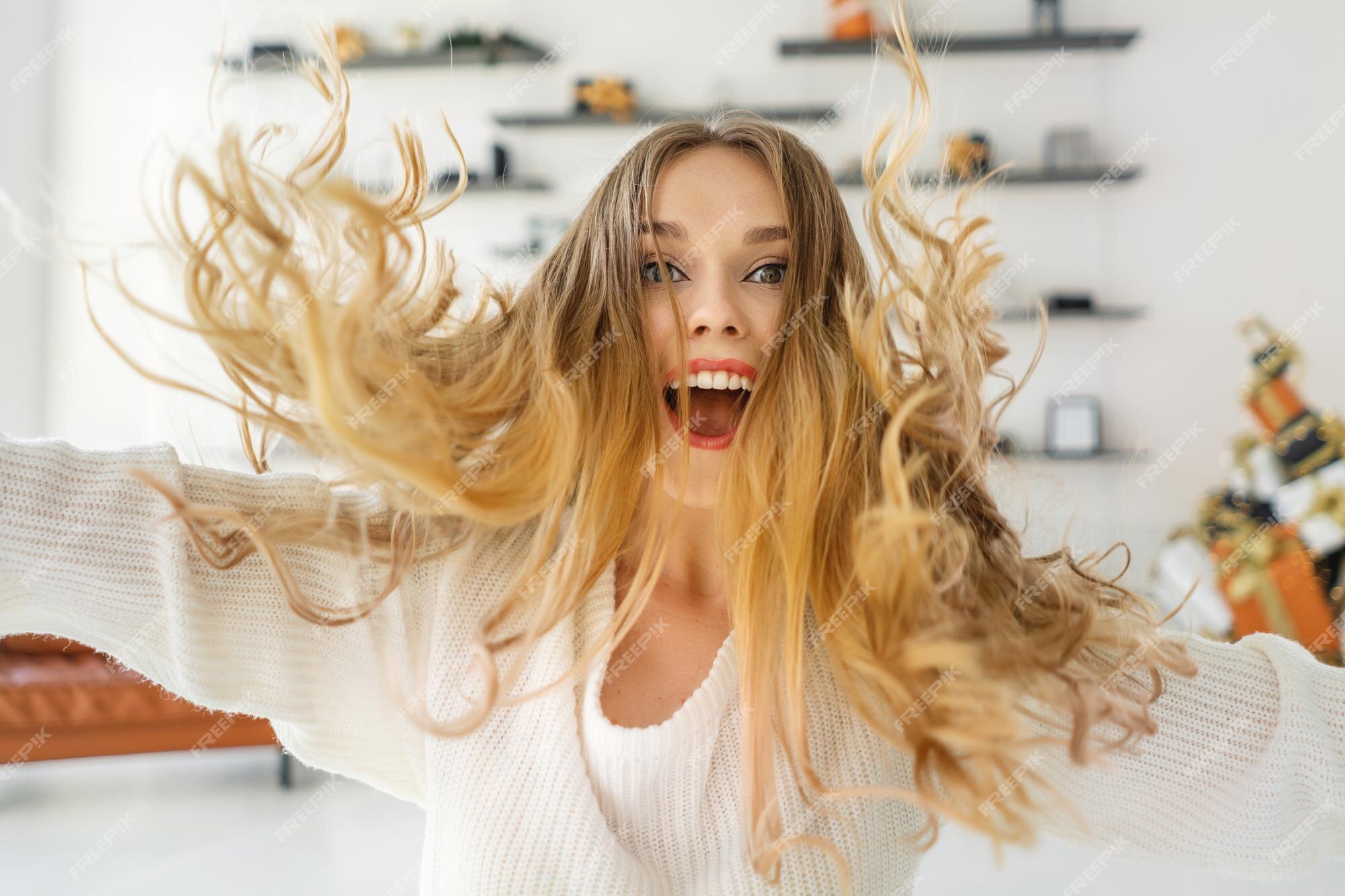 Menina bonita pulando e dançando em casa cabelo cacheado estilo casual  suéter branco feliz