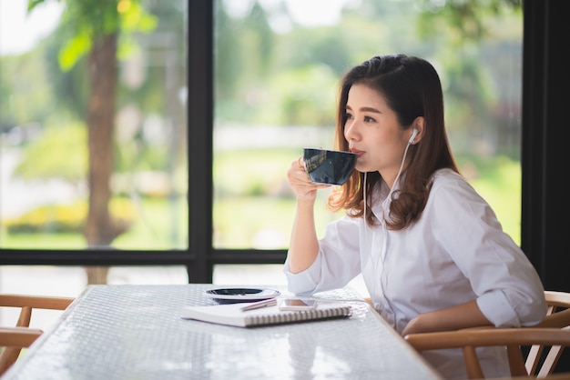 Menina bonita que trabalha no café e beber um pouco de café