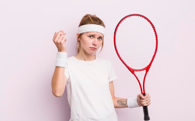 Menina bonita ruiva fazendo gesto de capice ou dinheiro dizendo para você pagar o conceito de tênis