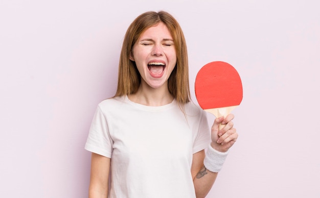 Menina bonita ruiva gritando agressivamente olhando muito irritado conceito de pingue-pongue