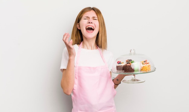 Menina bonita ruiva olhando desesperadamente frustrado e estressado conceito de bolos caseiros