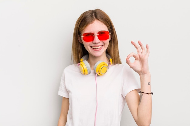 Menina bonita ruiva se sentindo feliz mostrando aprovação com gesto bem ouça o conceito de música