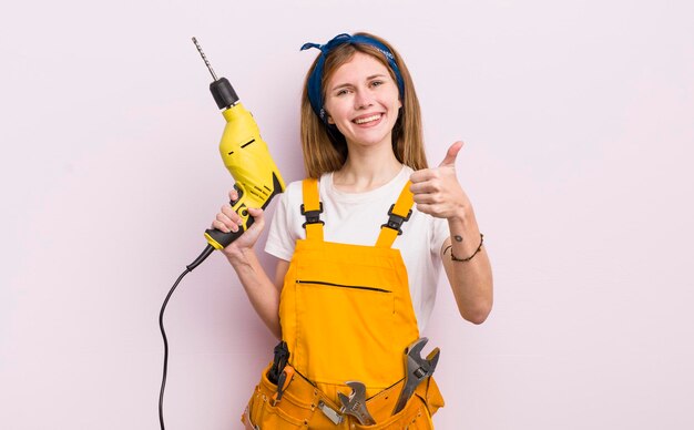 Menina bonita ruiva se sentindo orgulhosa sorrindo positivamente com polegares para cima conceito de renovação em casa