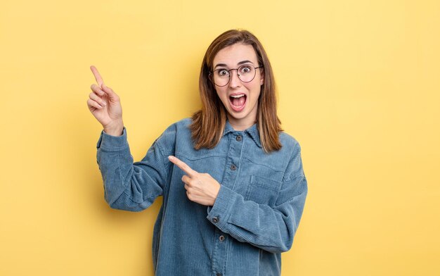 Menina bonita se sentindo alegre e surpresa, sorrindo com uma expressão chocada e apontando para o lado