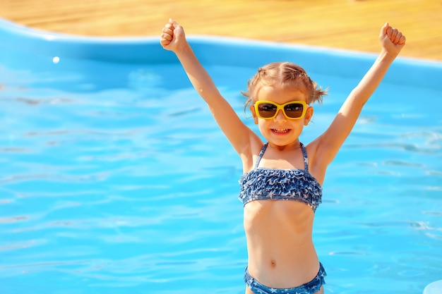 Menina bonita, segurando as mãos perto de uma piscina