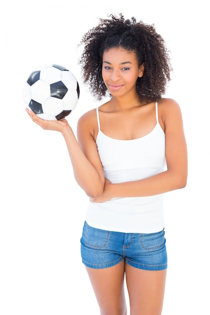 Menina bonita segurando futebol e sorrindo para a câmera