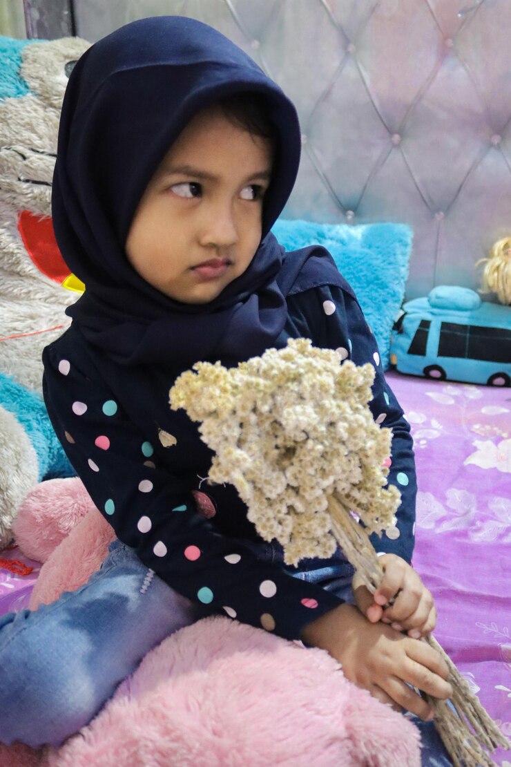 Foto menina bonita segurando um brinquedo enquanto está sentada ao ar livre