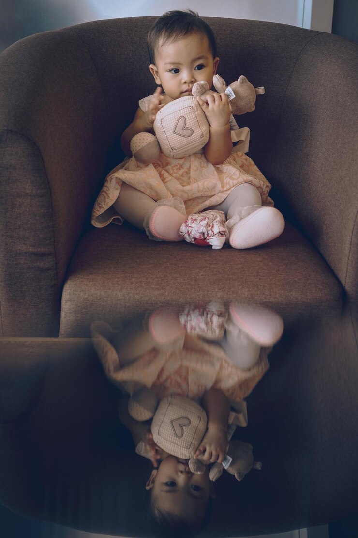 Foto menina bonita segurando um brinquedo macio enquanto está sentada no sofá em casa