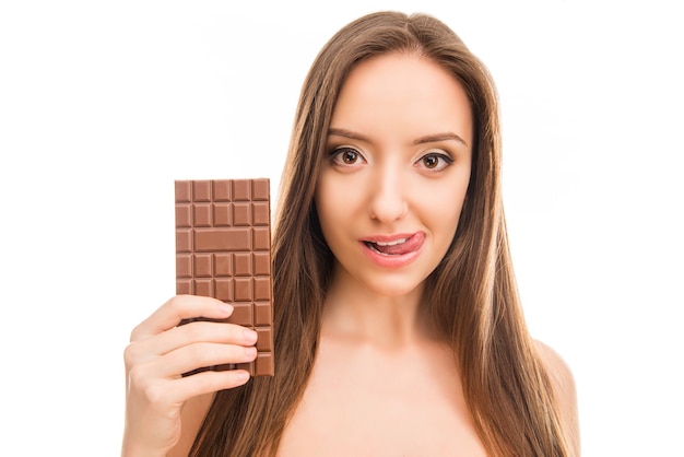 Menina bonita segurando uma barra de chocolate e lambendo os lábios