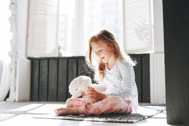 Foto menina bonita sentada no chão com um brinquedo na casa de banho brilhante