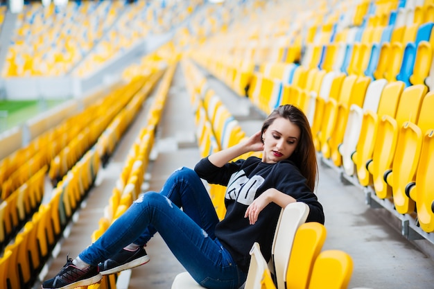 Menina bonita sentada no estádio da escola. Descanse do estudo.