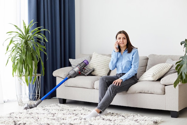 Menina bonita sentada no sofá em uma aconchegante sala de estar e falando ao telefone