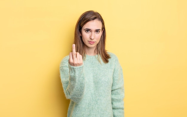 Menina bonita sentindo-se zangada, irritada, rebelde e agressiva, sacudindo o dedo do meio e reagindo