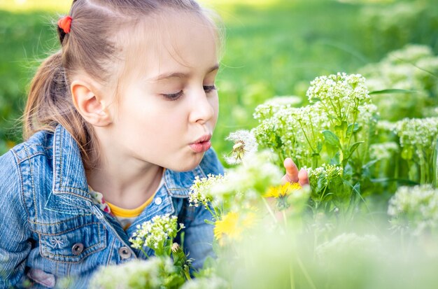 Menina bonita soprando flores dente de leão no parque verde