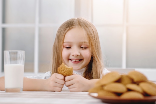 Menina bonita sorri enquanto come biscoito doce
