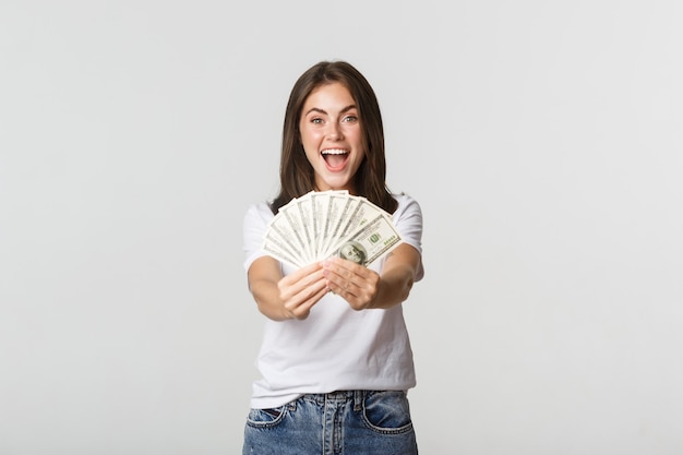 Menina bonita sorridente, dando-lhe dinheiro, parabenizando com vitória.