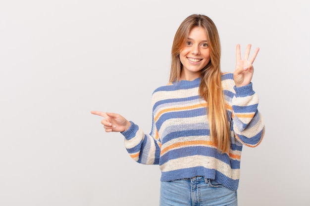 Menina bonita sorrindo e parecendo amigável, mostrando o número três