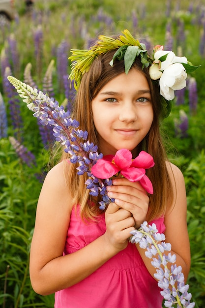 Menina bonita sorrindo em um vestido rosa no campo de tremoços.