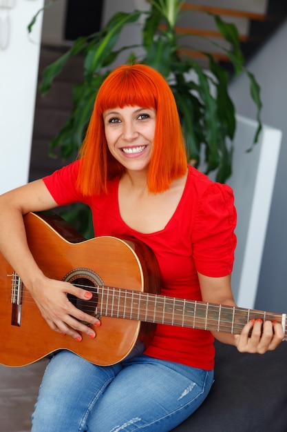 Menina bonita tocando violão no sofá