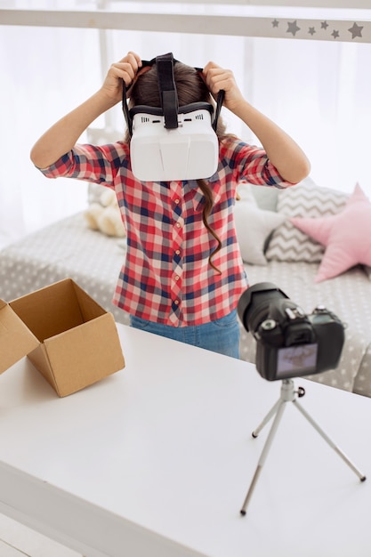 Menina bonita usando um fone de ouvido de realidade virtual na frente da câmera