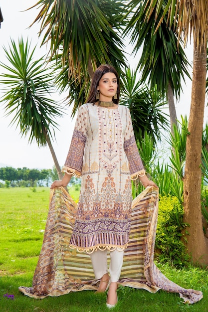 Menina bonita usando vestido tradicional segurando seu Dupatta para sessão de moda em um jardim