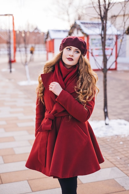 Menina bonita, vestindo um casaco vermelho e uma boina na rua de Natal