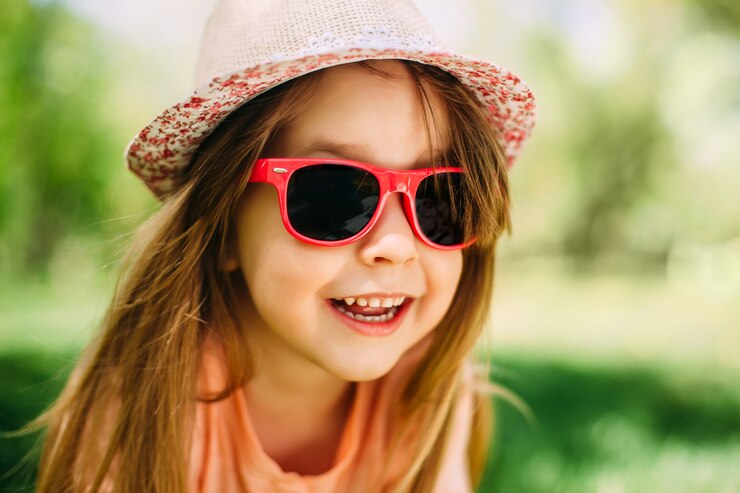 Menina bonita, vestindo um chapéu e óculos de sol ao ar livre