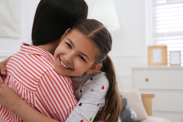Menina bonitinha abraçando a mãe na sala de estar Conceito de adoção