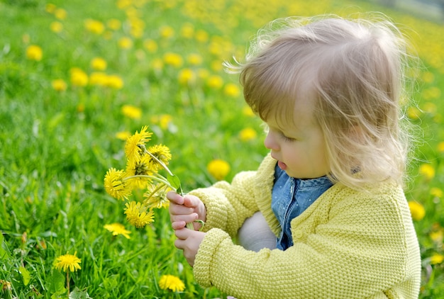 Menina bonitinha andando no parque com flores-leão