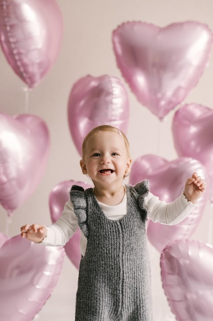 Menina bonitinha bebê de 1º aniversário com balões de hélio corações rosa
