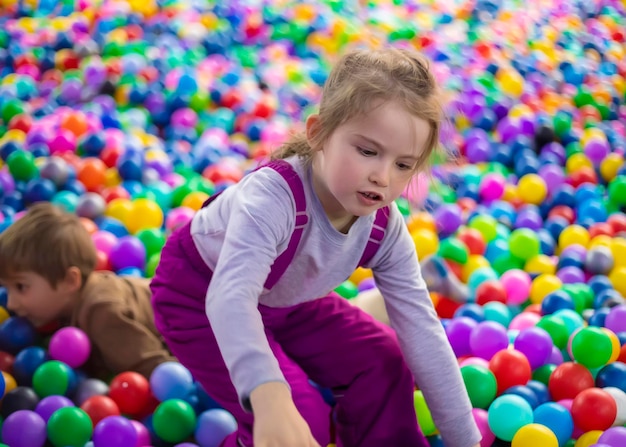 Menina bonitinha brinca com bolas de plástico no playcenter infantil