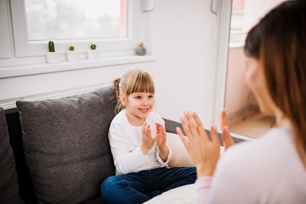 Menina bonitinha brincando com a mãe dentro de casa.