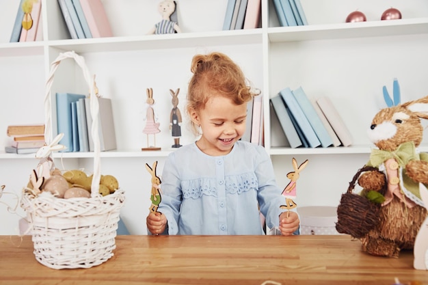 Menina bonitinha brincando com brinquedos ao celebrar as férias da Páscoa dentro de casa