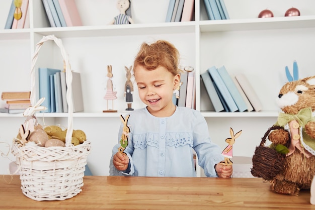 Menina bonitinha brincando com brinquedos ao celebrar as férias da Páscoa dentro de casa