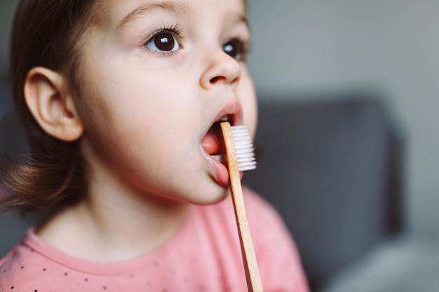 Menina bonitinha brincando com escova de dentes de bambu de madeira ecológica