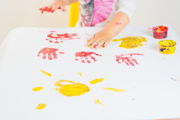 Foto menina bonitinha brincando com tintas coloridas em um fundo branco