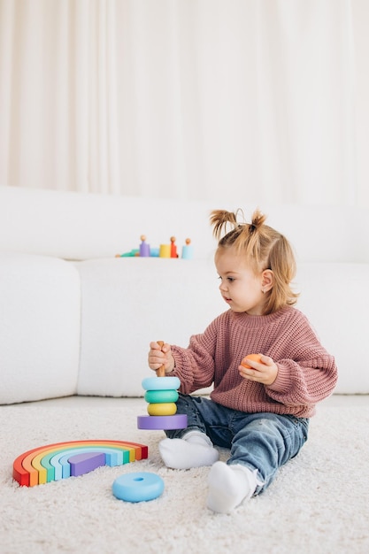 Menina bonitinha brincando em casa com brinquedos ecológicos de madeira Criança feliz cortando legumes e frutas com faca de brinquedo A criança jogando jogos educativos