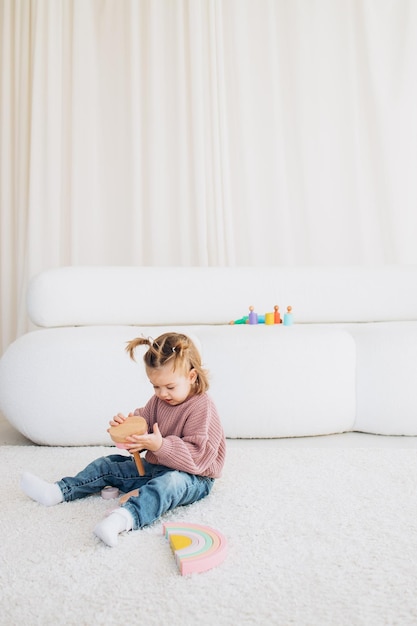 Menina bonitinha brincando em casa com brinquedos ecológicos de madeira Criança feliz cortando legumes e frutas com faca de brinquedo A criança jogando jogos educativos