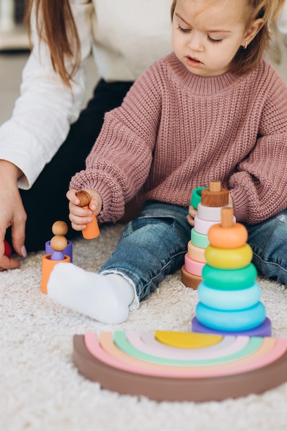 Menina bonitinha brincando em casa com brinquedos ecológicos de madeira Criança feliz cortando legumes e frutas com faca de brinquedo A criança jogando jogos educativos