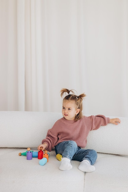 Foto menina bonitinha brincando em casa com brinquedos ecológicos de madeira criança feliz cortando legumes e frutas com faca de brinquedo a criança jogando jogos educativos