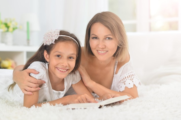 Menina bonitinha com a mãe lendo livro