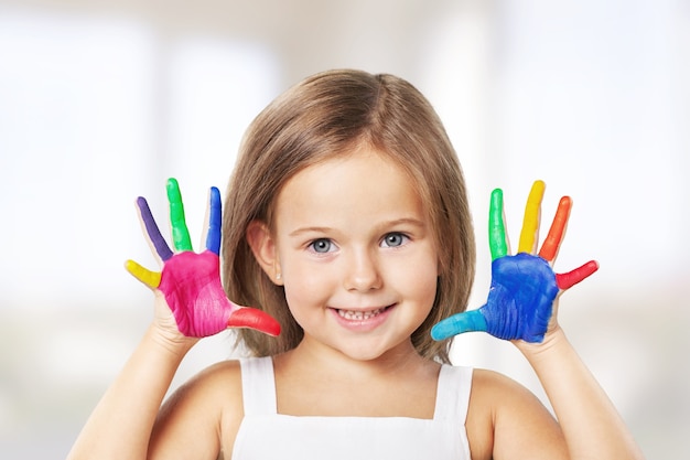 Menina bonitinha com as mãos pintadas de cores no fundo