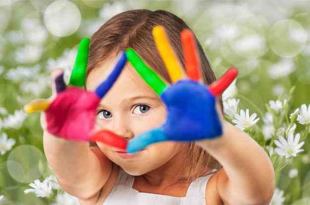 Menina bonitinha com as mãos pintadas de cores no fundo