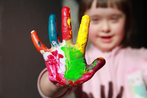 Menina bonitinha com as mãos pintadas.