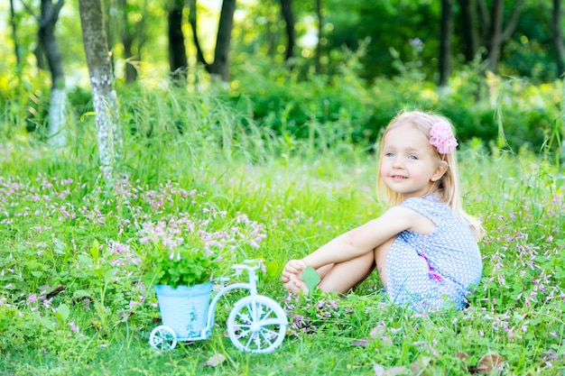 Feliz Bebê Loira Com Duas Pequenas Tranças Em Camiseta Branca E Um Kit De  Calças Jeans Sentado Sobre O Fundo Da Grama Verde Foto de Stock - Imagem de  pouco, inocência: 143643548