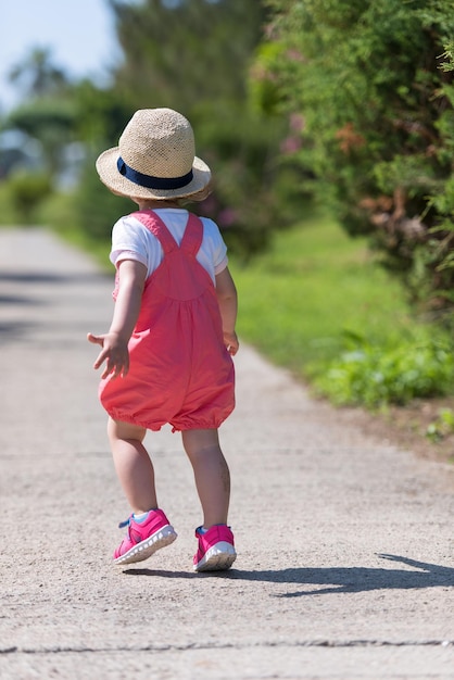 Foto menina bonitinha com chapéu alegremente passando o tempo enquanto corre no parque na manhã de verão