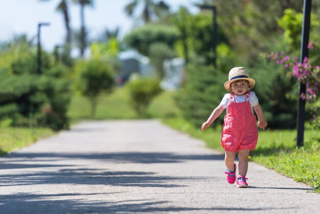 Foto menina bonitinha com chapéu alegremente passando o tempo enquanto corre no parque na manhã de verão