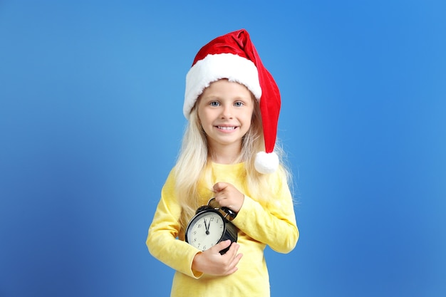 Menina bonitinha com chapéu de Papai Noel com relógio. Conceito de contagem regressiva de natal